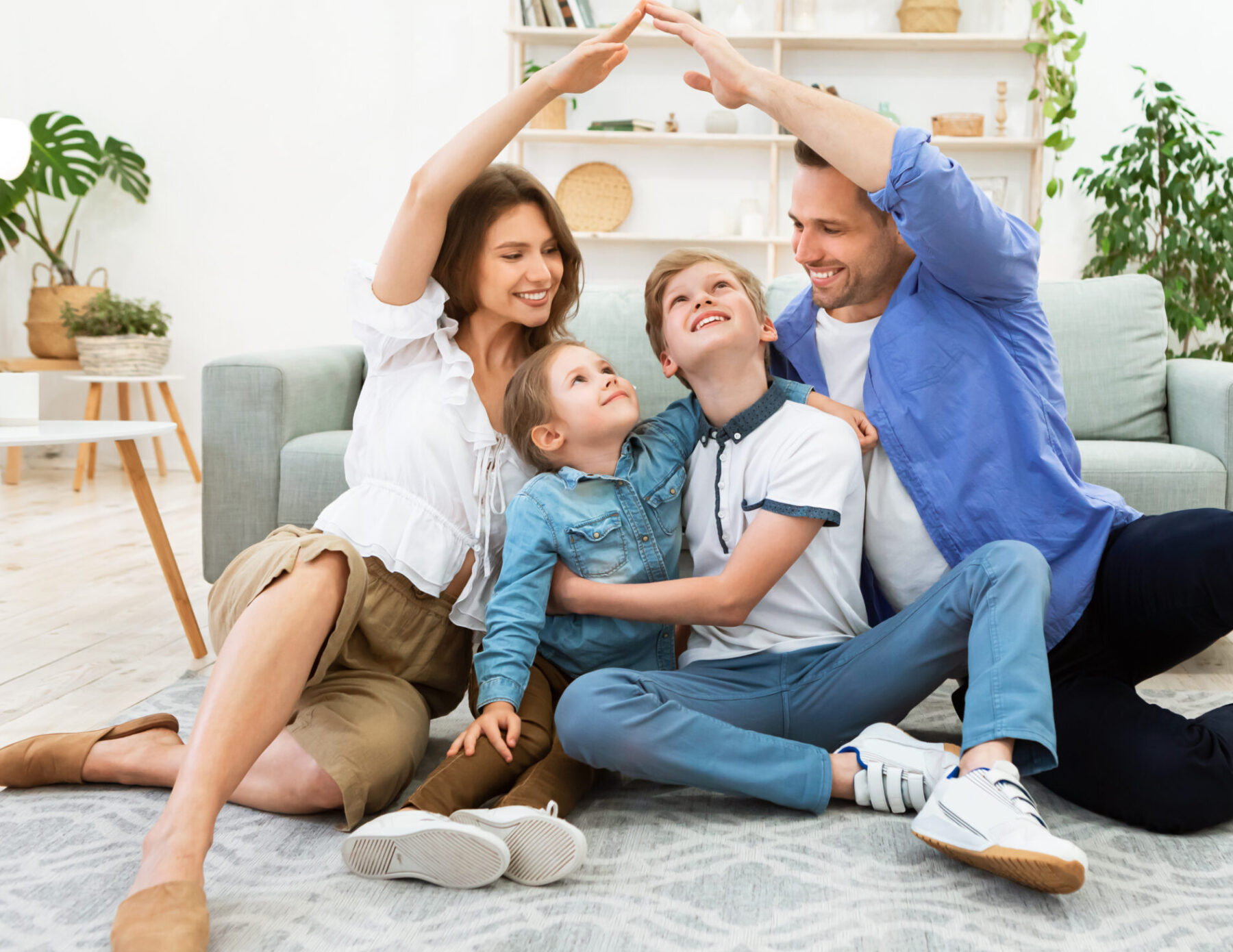 Young parents joining hands making roof sitting with children indoor